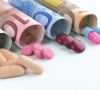 Pillen und Tabletten vor Euro-Banknoten als Kostensymbol