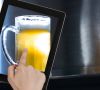 Hand taking picture of beer glass through digital tablet